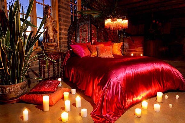 Chambre romantique décorée avec des draps rouges en satin et des bougies