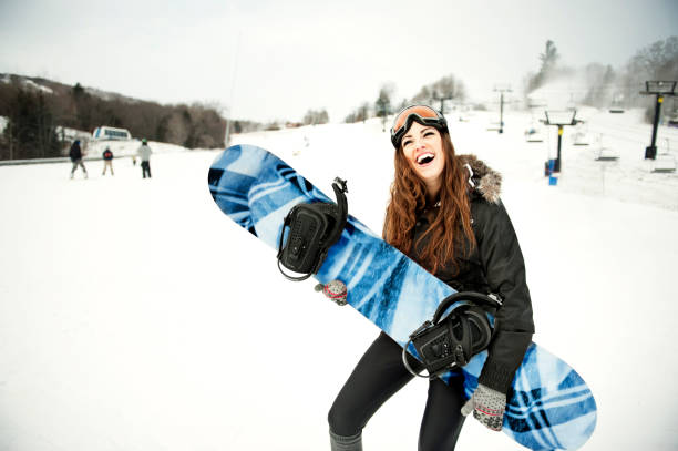 Jeune femme sur les pistes avec une planche de snowboard