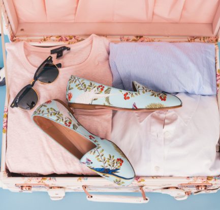 valise ouverte vue de dessus avec chaussures vêtements et lunettes de soleil